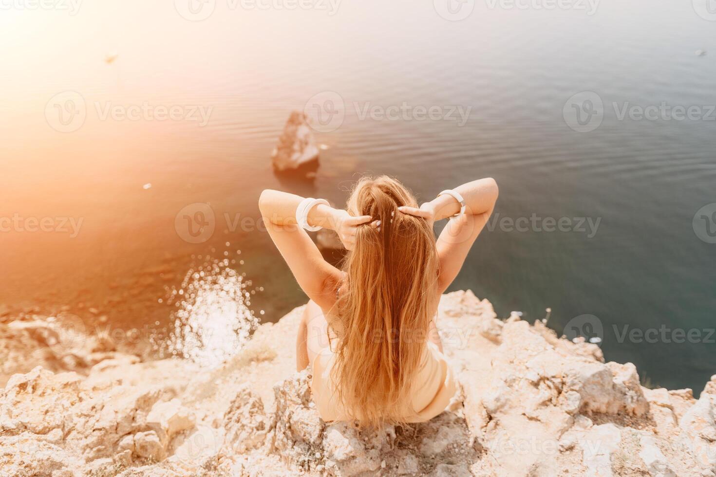 Woman travel sea. Happy tourist enjoy taking picture outdoors for memories. Woman traveler looks at the edge of the cliff on the sea bay of mountains, sharing travel adventure journey photo