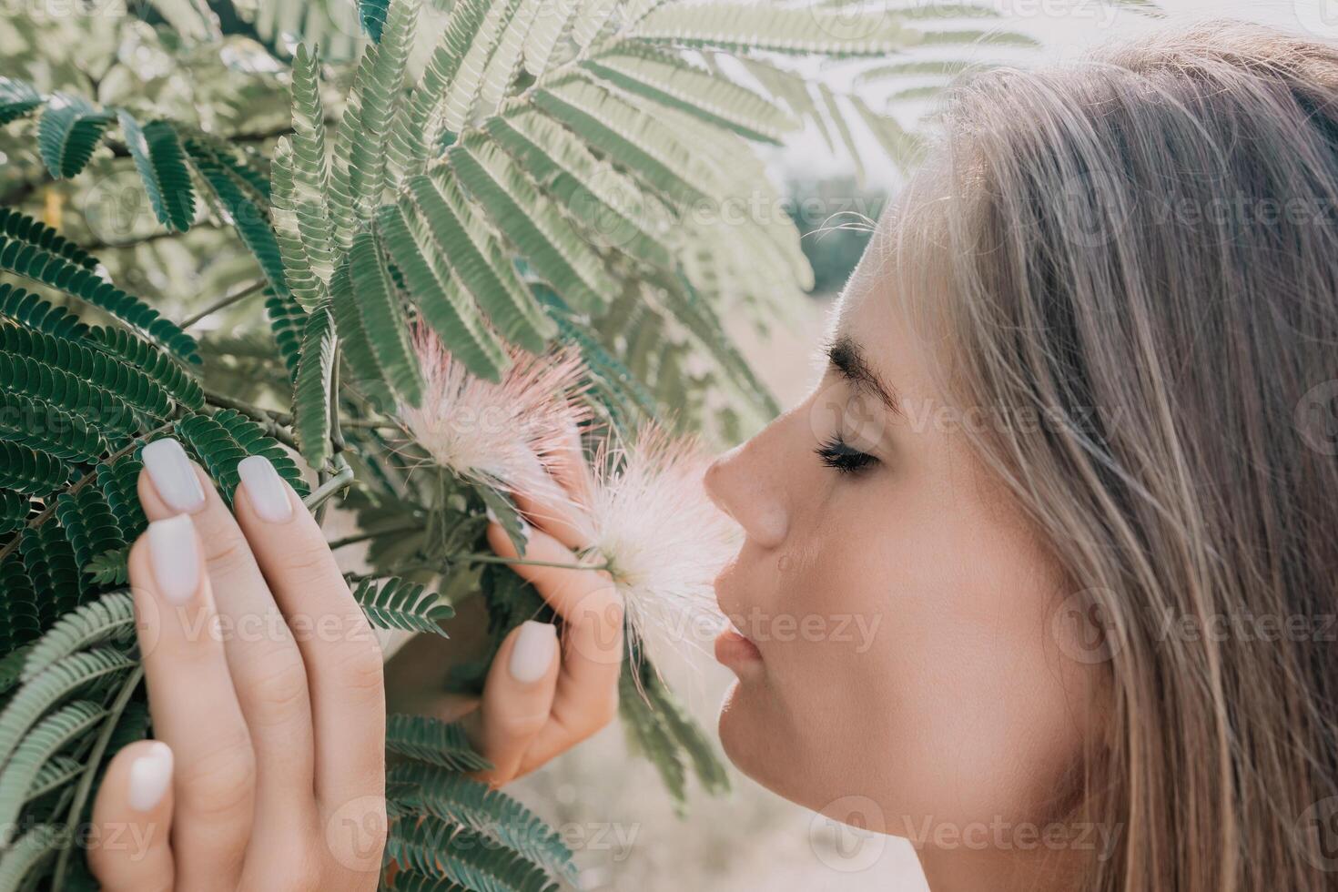 Beauty portrait of happy woman closeup. Young girl smelling Chinese acacia pink blossoming flowers. Portrait of young woman in blooming spring, summer garden. Romantic vibe. Female and nature photo