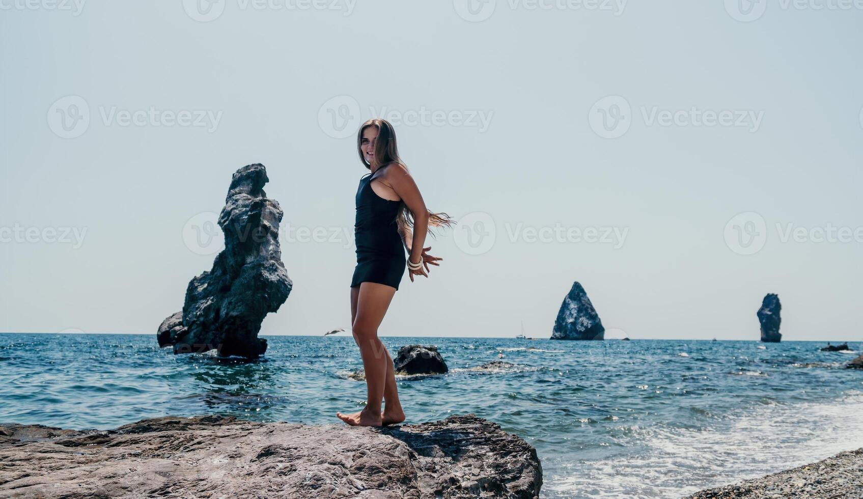 mujer verano viaje mar. contento turista en sombrero disfrutar tomando imagen al aire libre para recuerdos. mujer viajero posando en el playa a mar rodeado por volcánico montañas, compartiendo viaje aventuras viaje foto