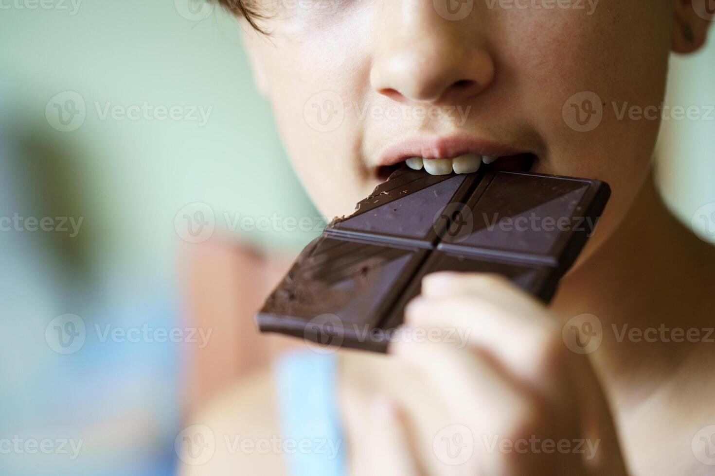 Unrecognizable girl eating delicious chocolate bar at home photo