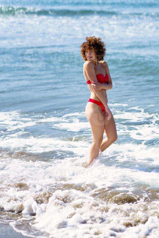 Happy female smiling while standing in wavy sea photo