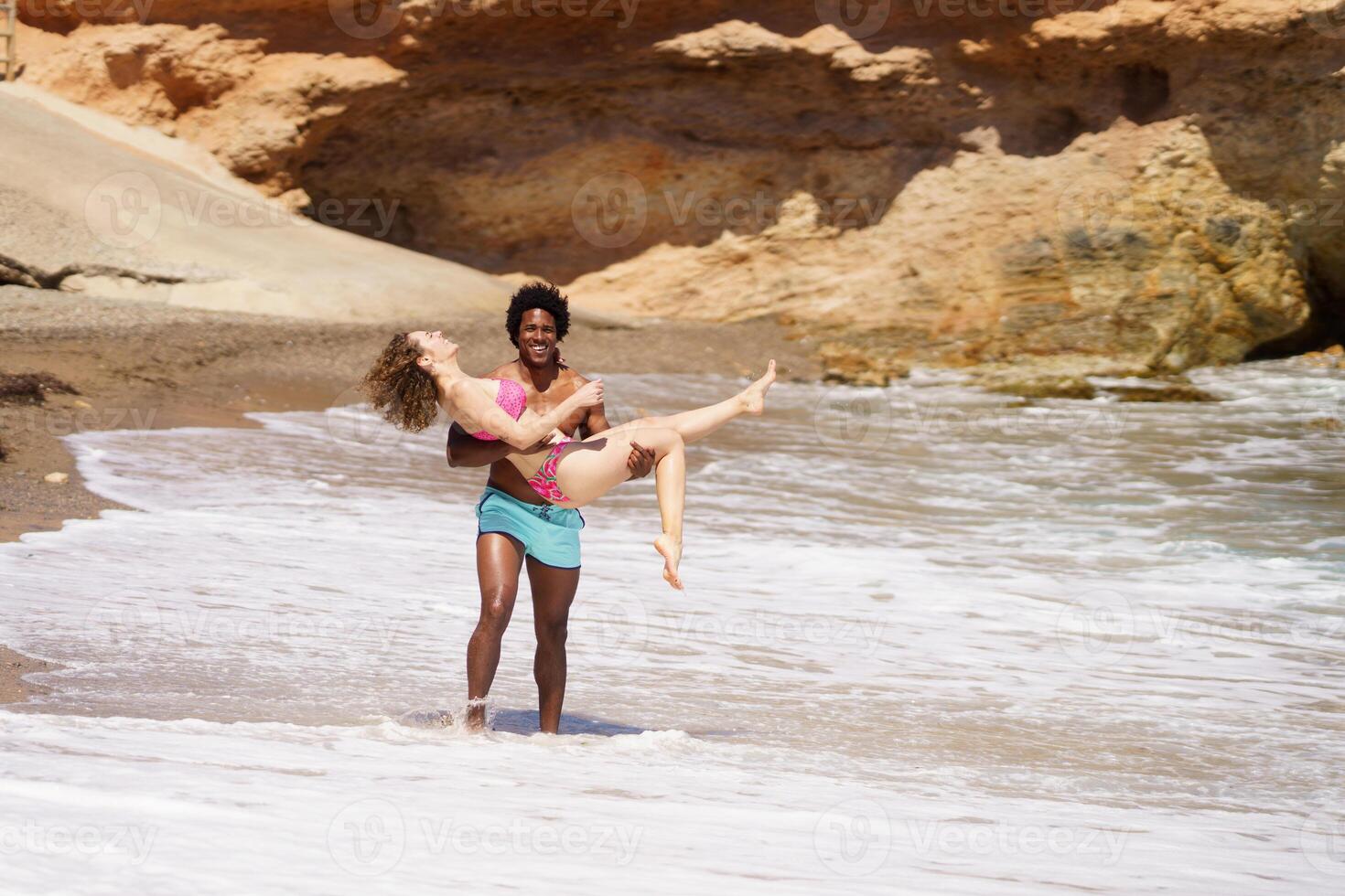 Happy diverse couple having fun on beach photo