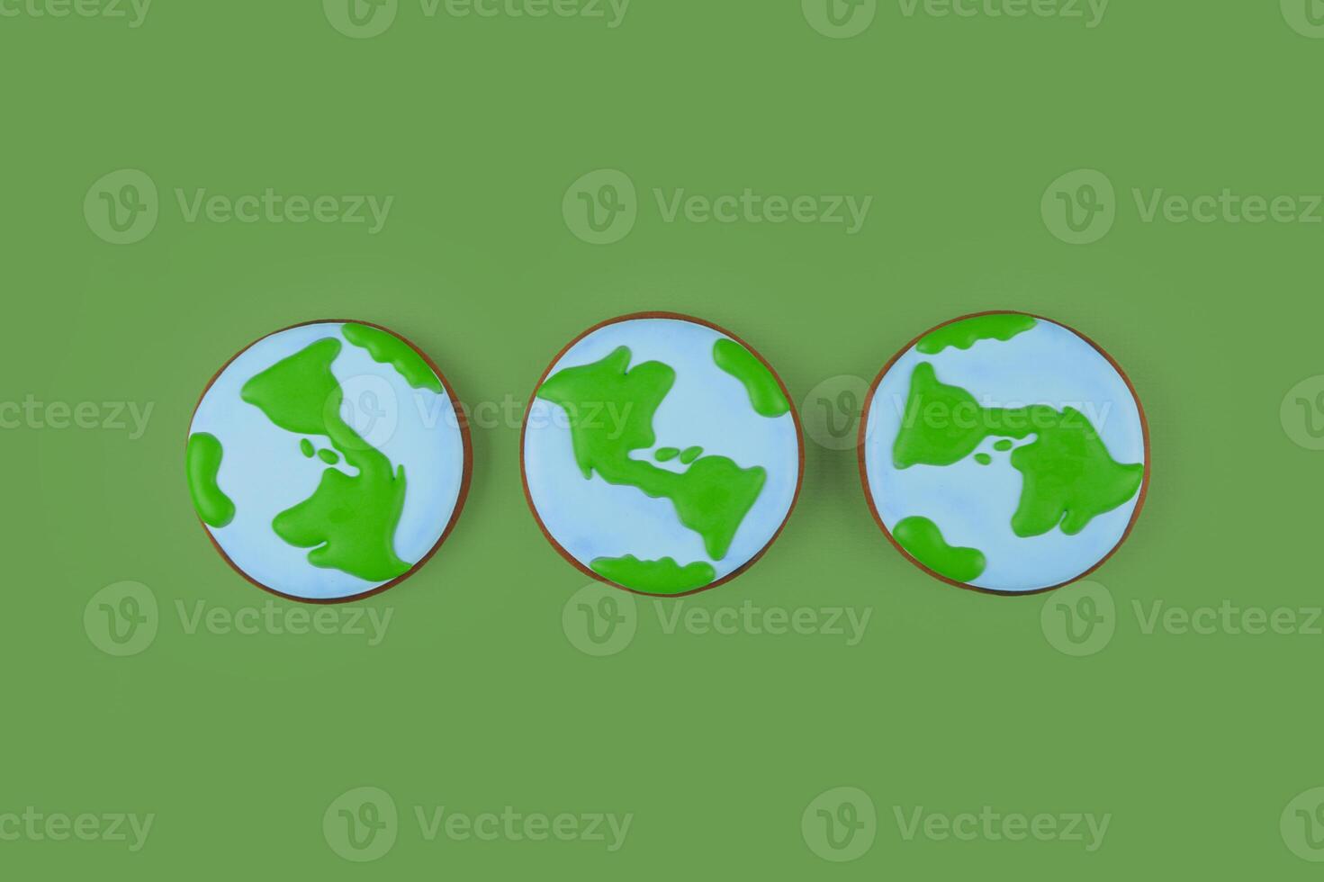 Earth Day concept. Three cookies in shape of Earth on green backdrop. photo