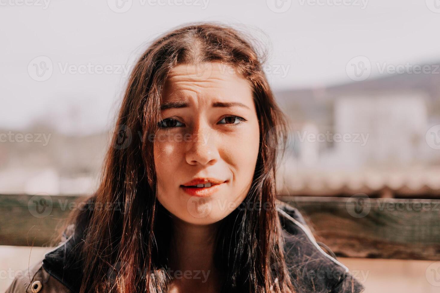 Happy young smiling woman with freckles outdoors portrait. Soft sunny colors. Outdoor close-up portrait of a young brunette woman and looking to the camera, posing against autumn nature background photo