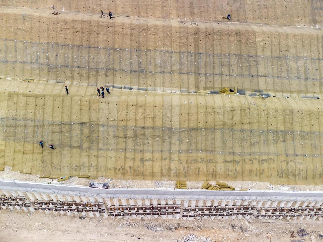 Mountain road constraction. Workers reinforce the slope over the new road. Road construction in progress on slope nature canyon. Infrastructure development and logistics. Aerial drone shot photo