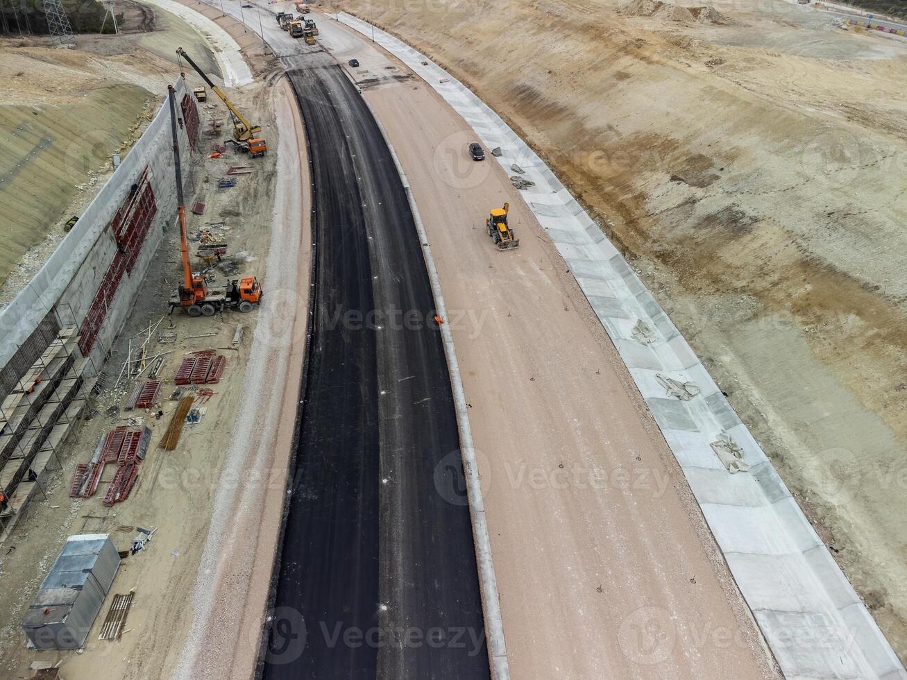 Mountain road constraction. Workers reinforce the slope over the new road. Road construction in progress on slope nature canyon. Infrastructure development and logistics. Aerial drone shot photo