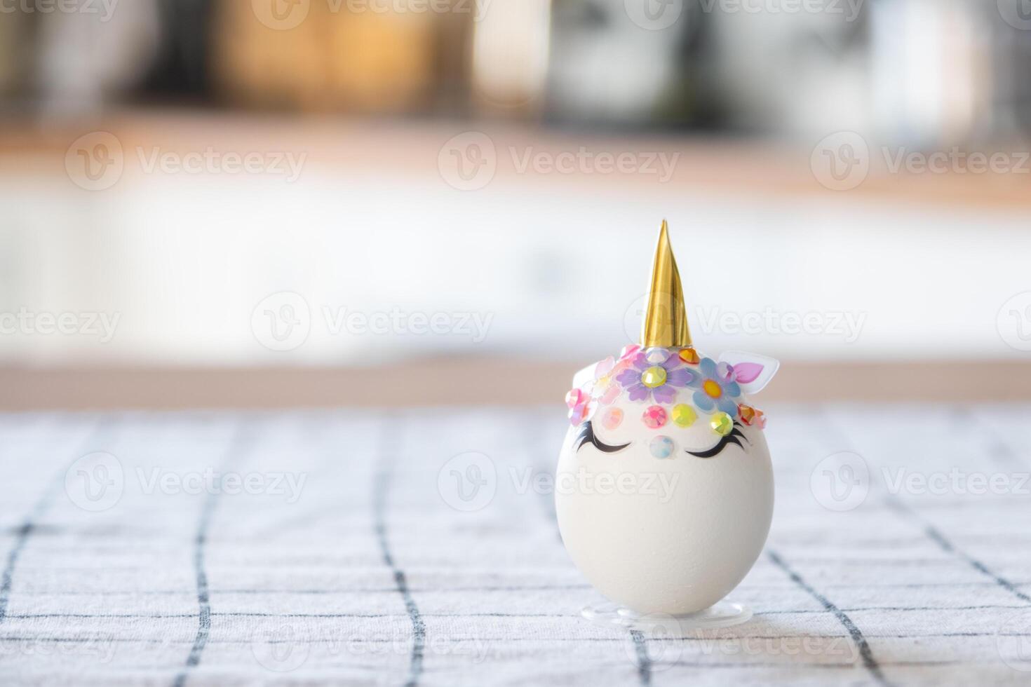 Easter craft - decorates an egg in the form of a unicorn with rhinestones, horn, flowers in the interior of a house photo