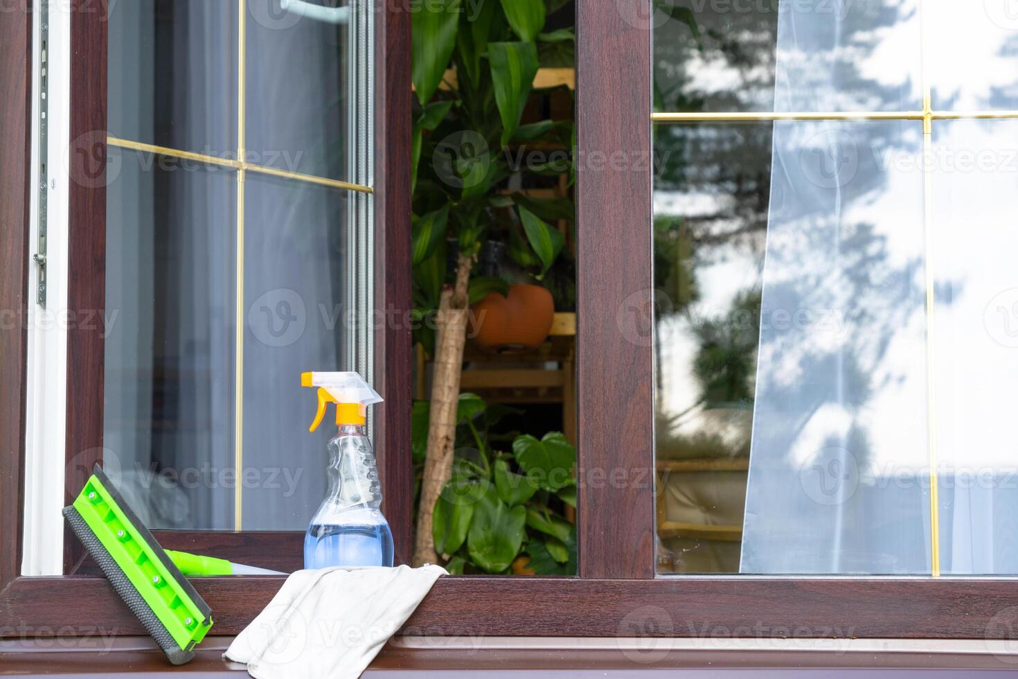 A window cleaning spray, a rag and a mop stand on the window sill of an open window outside for spring general cleaning photo