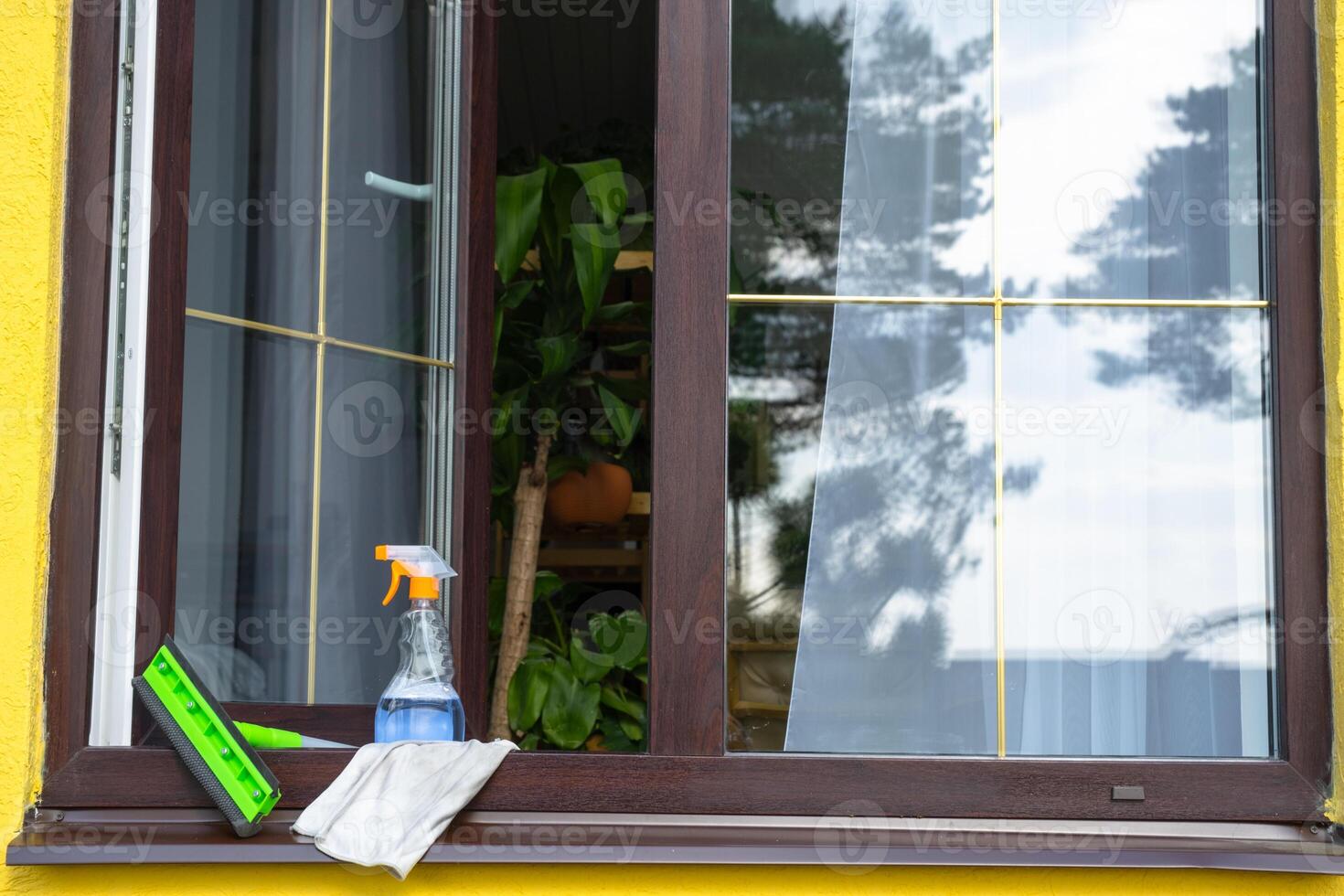 A window cleaning spray, a rag and a mop stand on the window sill of an open window outside for spring general cleaning photo