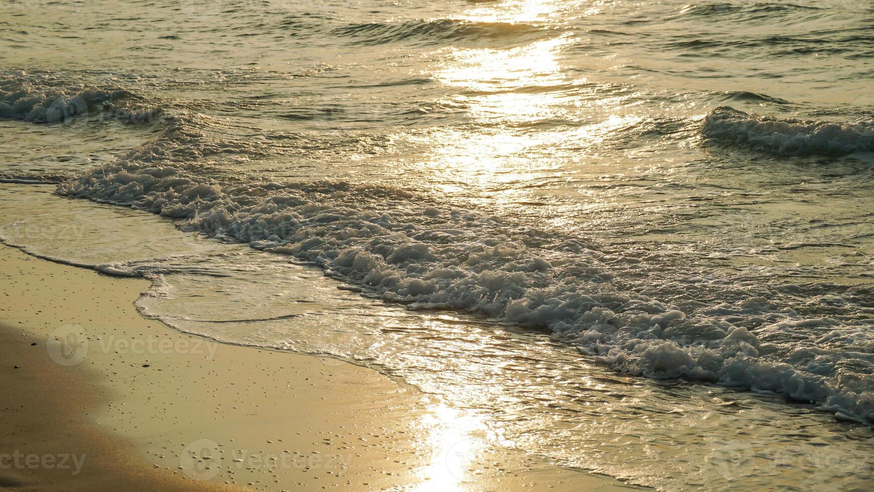 Beautiful sunset beach abstract texture background. Close up soft wave lapped the sandy beach, Summer Background. Beautiful sea waves with foam of golden color isolated. photo
