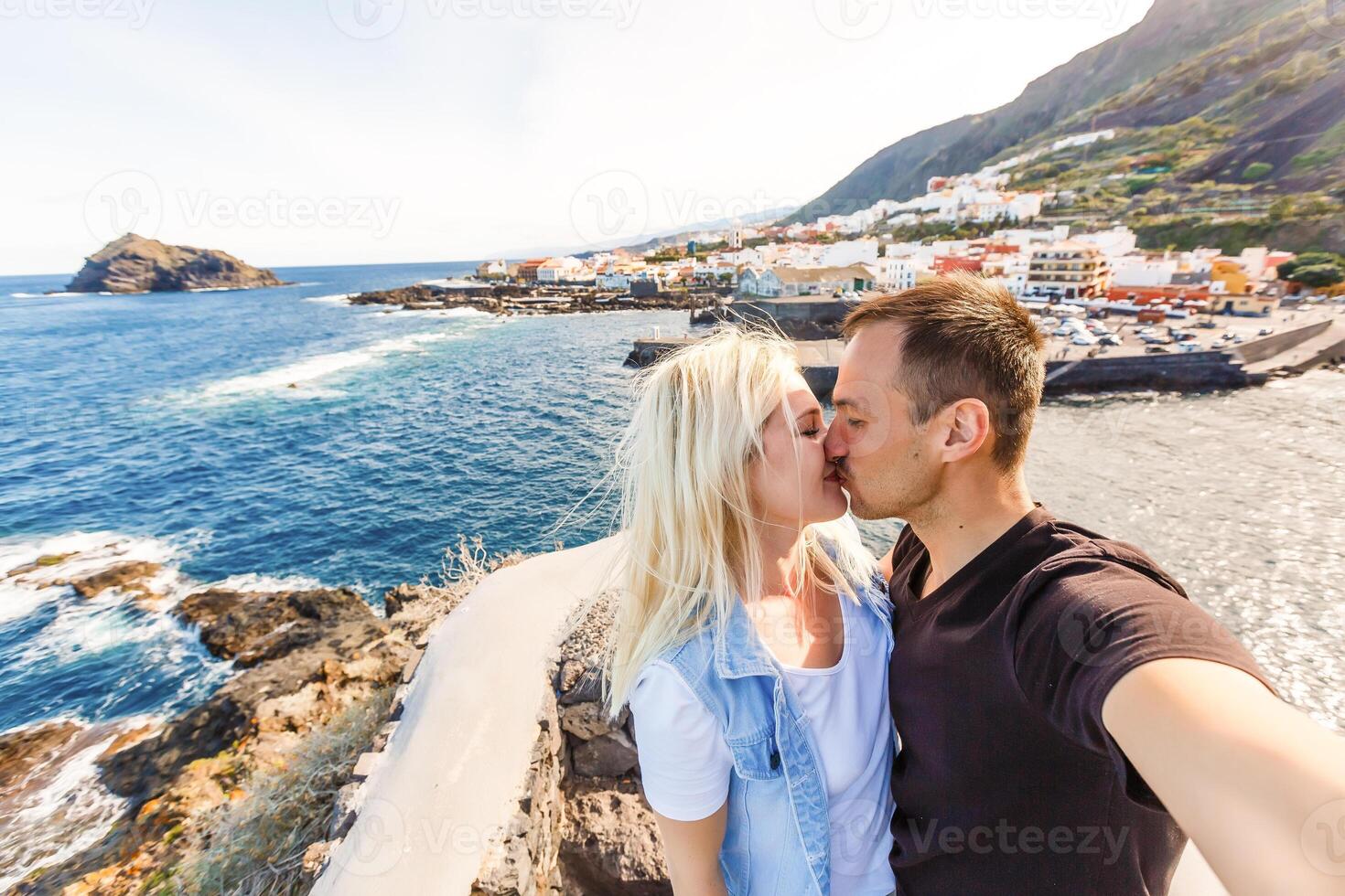 Young girl smiling and speaking consulting and giving instruction with voice recognition. Woman with audio recording in smart phone in the seaside in Garachico, Tenerife photo