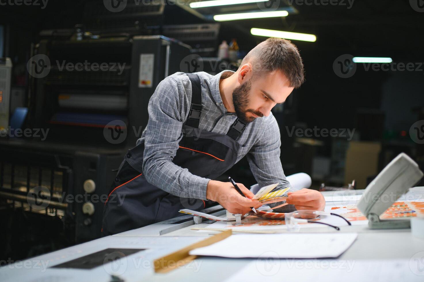 Print house worker controlling printing process quality and checking colors with magnifying glass photo