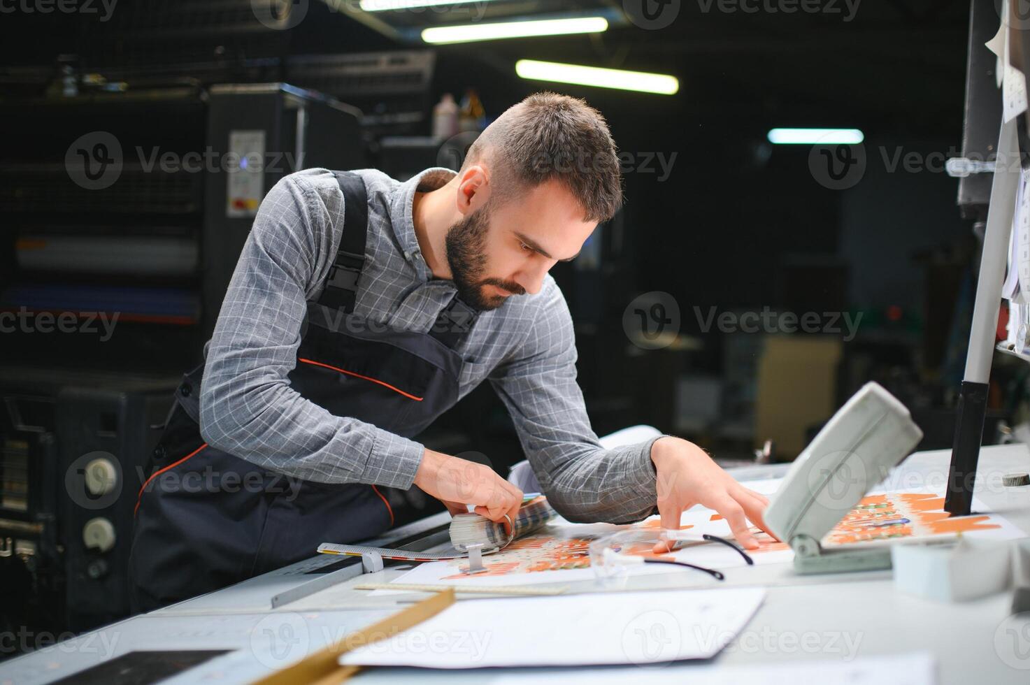 Man working in printing house with paper and paints photo