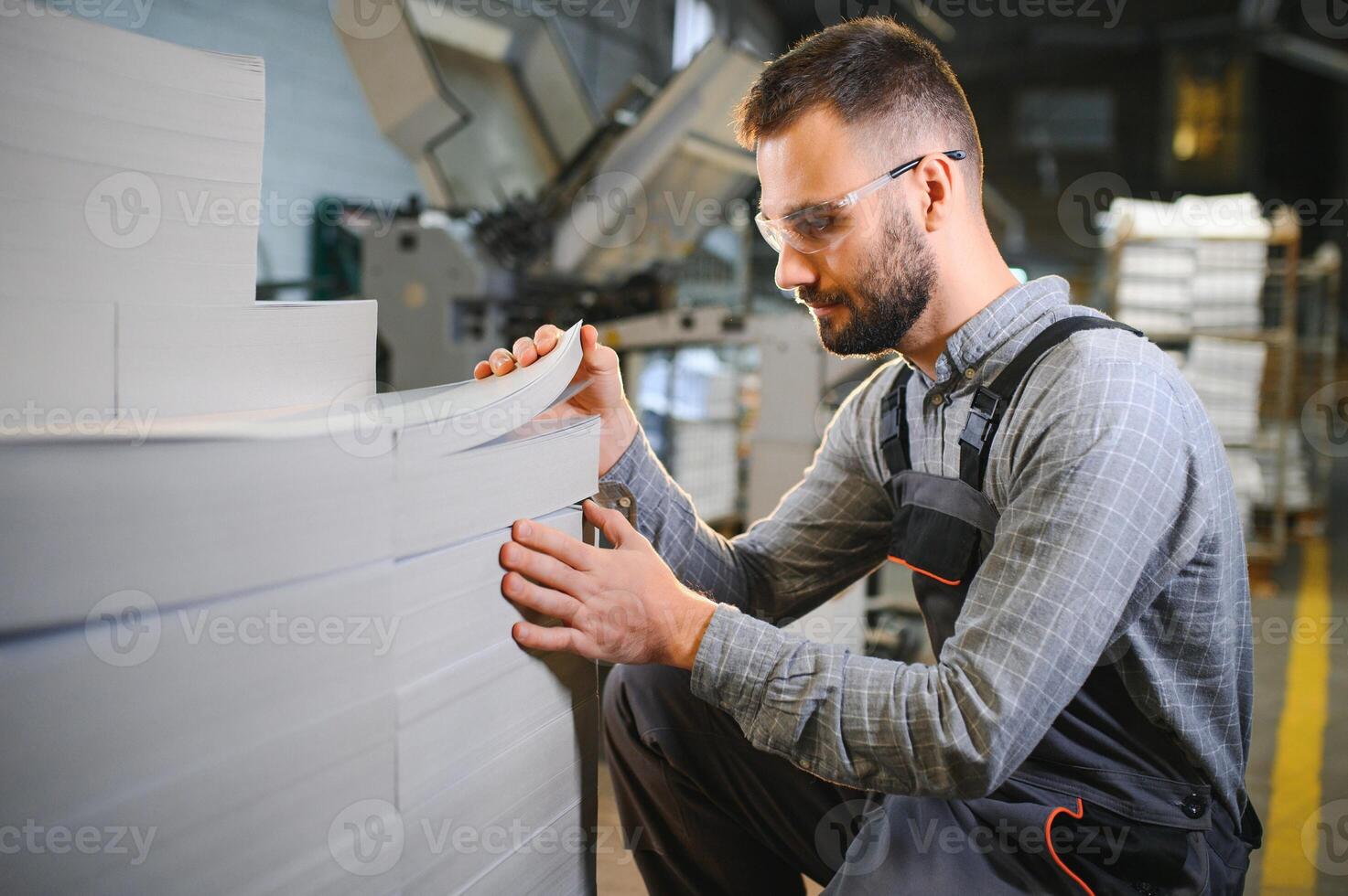 Man working in printing house with paper and paints photo