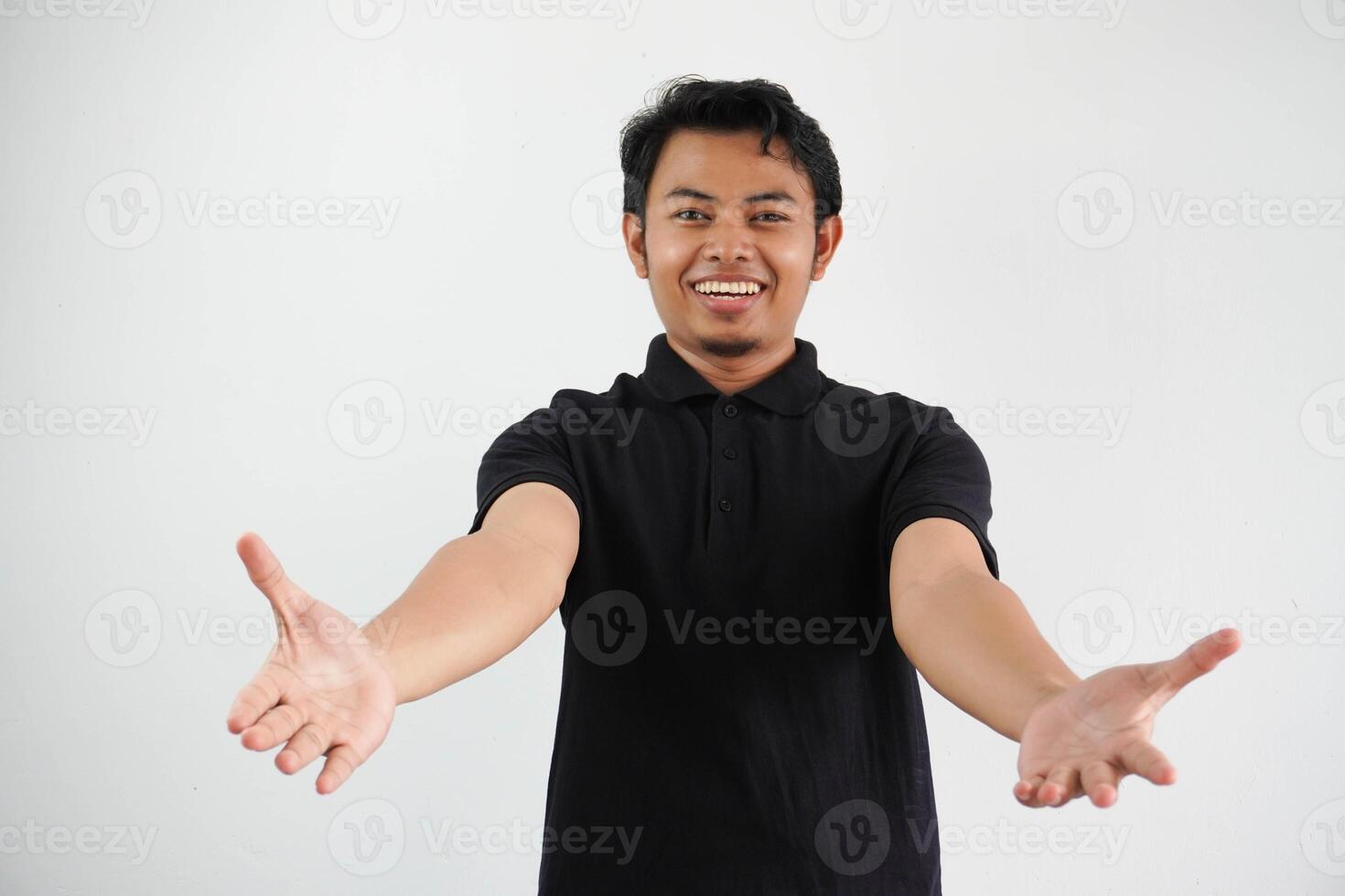young Asian man feels confident giving a hug to the camera, wearing black polo t shirt isolated on white background photo