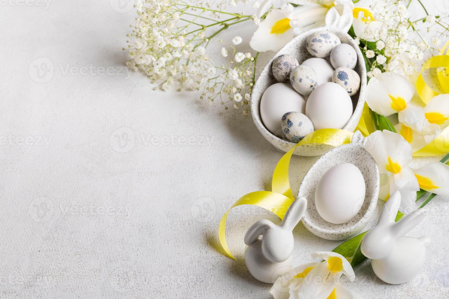 Easter festive card with eggs in plates with bunny ears, small bunnies, flowers on white. Copy space photo