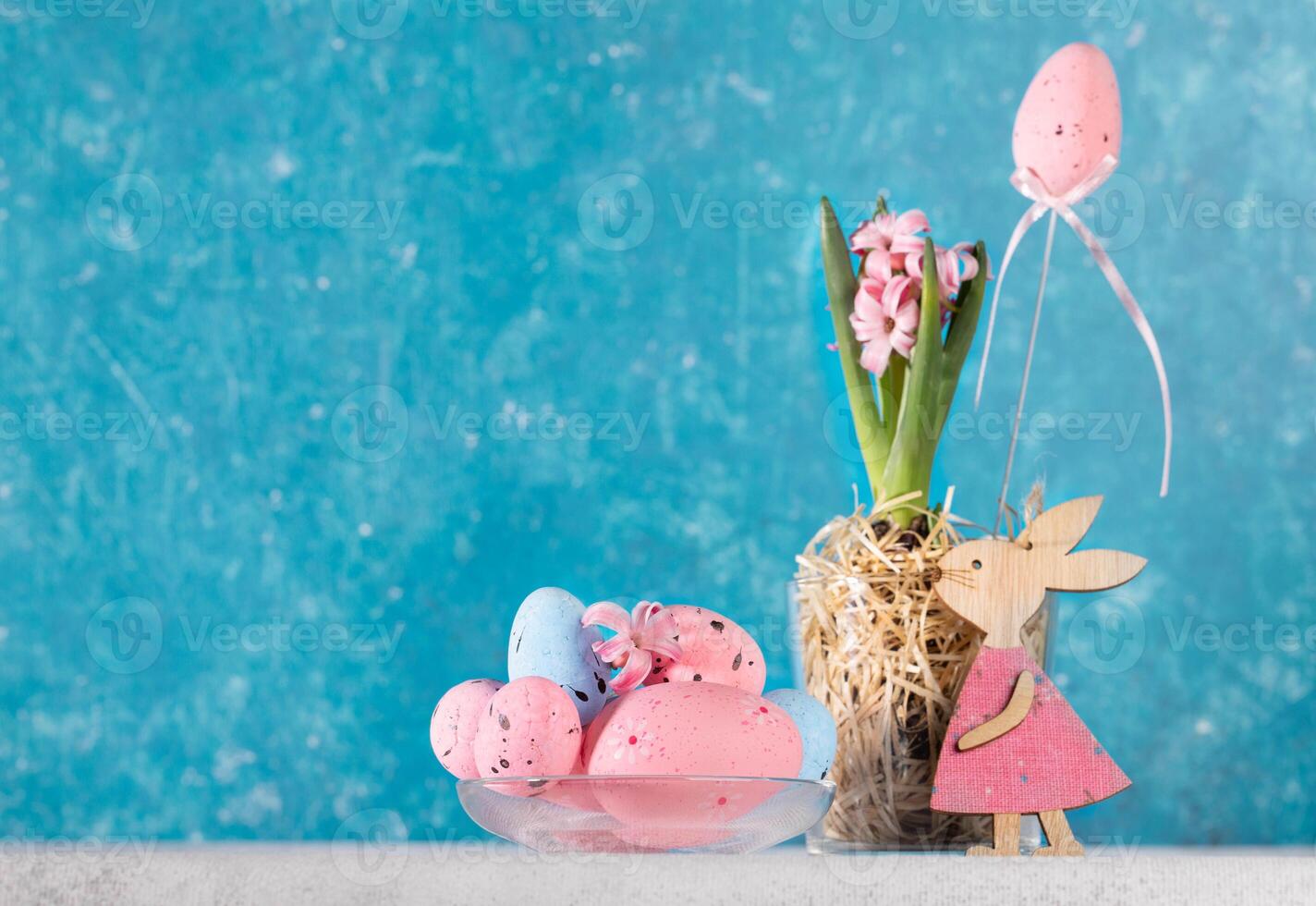 Vivid holiday card with pink Easter decorations on white table with turquoise backdrop. Copy space. photo