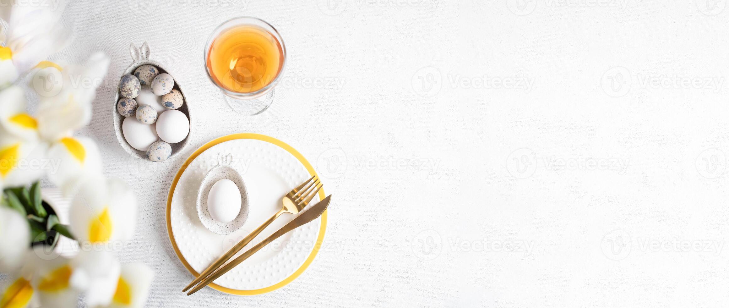 Easter white yellow table serving. Eggs, plates, golden cutlery, rose wine glass Top view Copy space photo