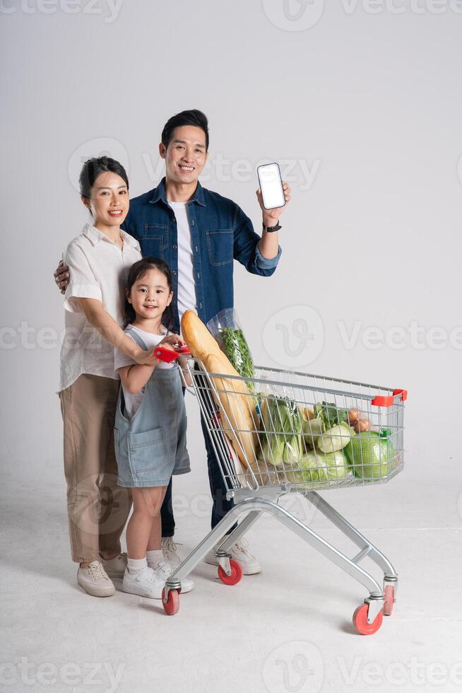 Image of Asian family pushing a supermarket cart while shopping, isolated on white background photo