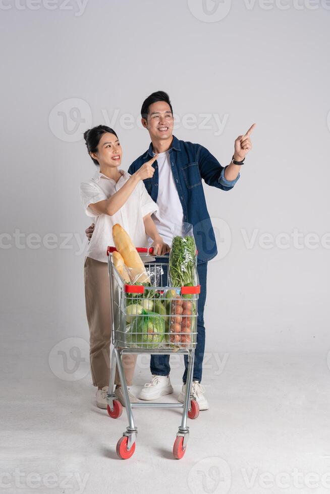 Image of Asian couple pushing supermarket cart while shopping, isolated on white background photo