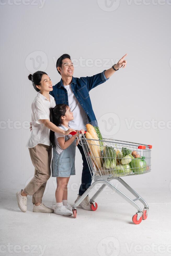 Image of Asian family pushing a supermarket cart while shopping, isolated on white background photo