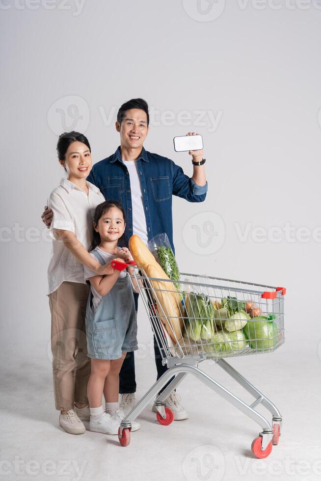 Image of Asian family pushing a supermarket cart while shopping, isolated on white background photo