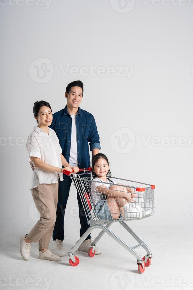 Image of Asian family pushing a supermarket cart while shopping, isolated on white background photo