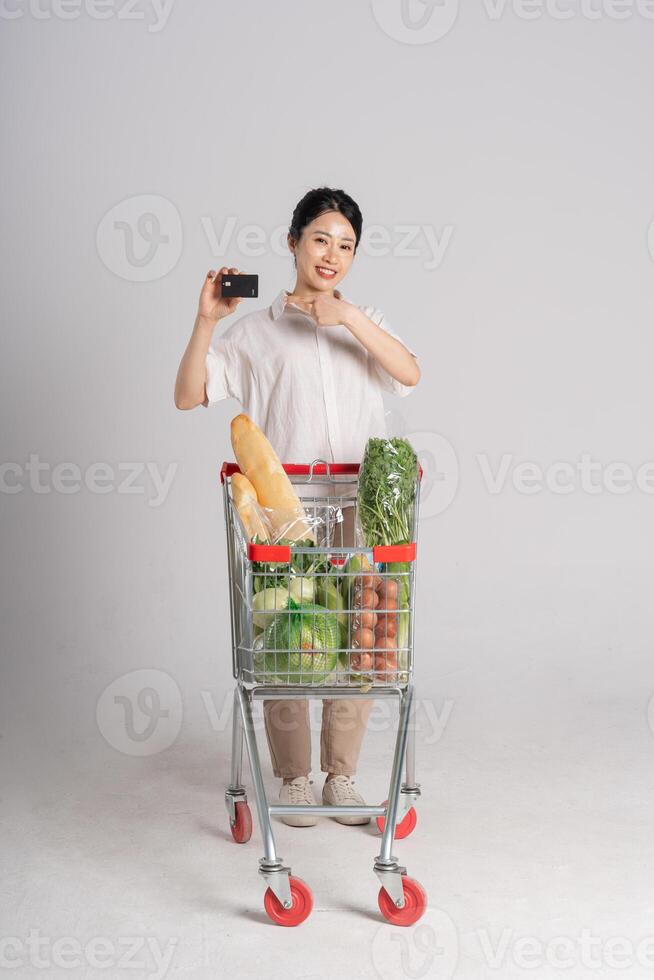 Smiling woman happily pushing a supermarket cart, isolated on white background photo