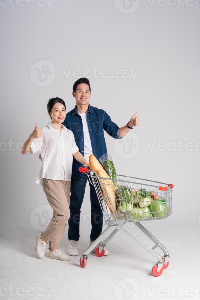 Image of Asian couple pushing supermarket cart while shopping, isolated on white background photo