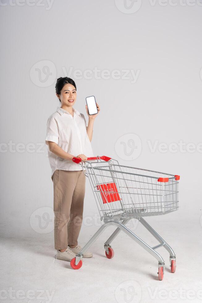Smiling woman happily pushing a supermarket cart, isolated on white background photo
