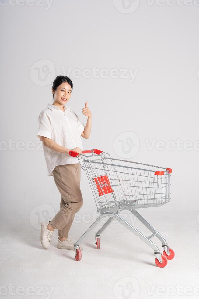 Smiling woman happily pushing a supermarket cart, isolated on white background photo