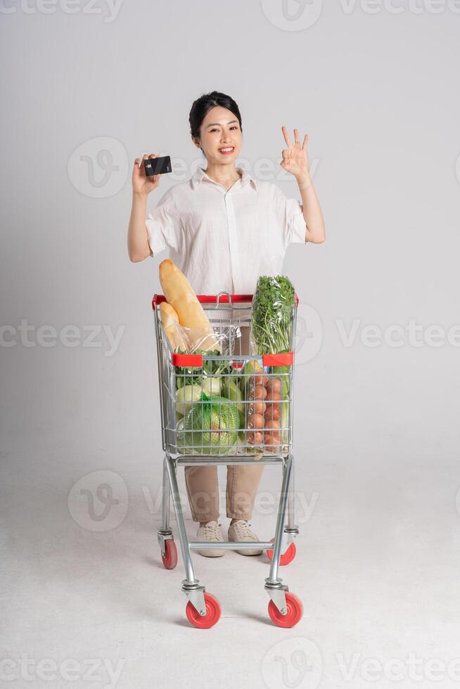 Smiling woman happily pushing a supermarket cart, isolated on white background photo