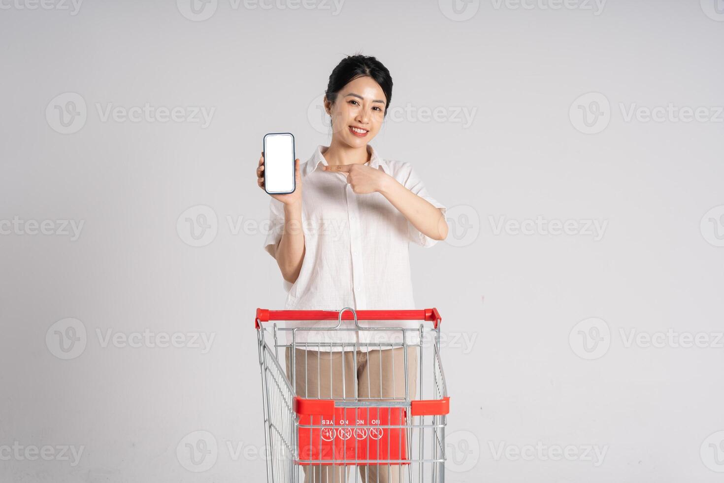 Smiling woman happily pushing a supermarket cart, isolated on white background photo