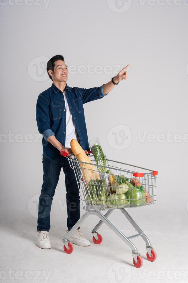 Happy smiling man pushing supermarket cart isolated on white background photo