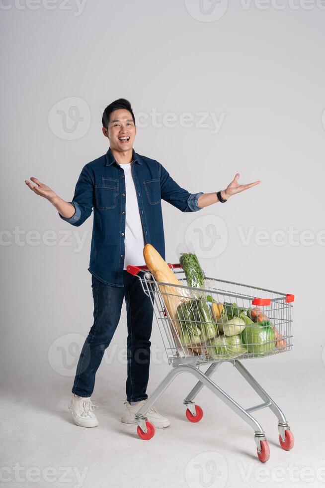 Happy smiling man pushing supermarket cart isolated on white background photo