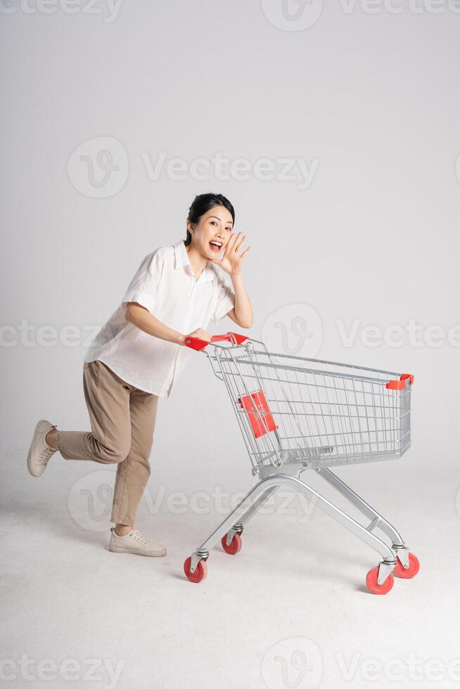 Smiling woman happily pushing a supermarket cart, isolated on white background photo
