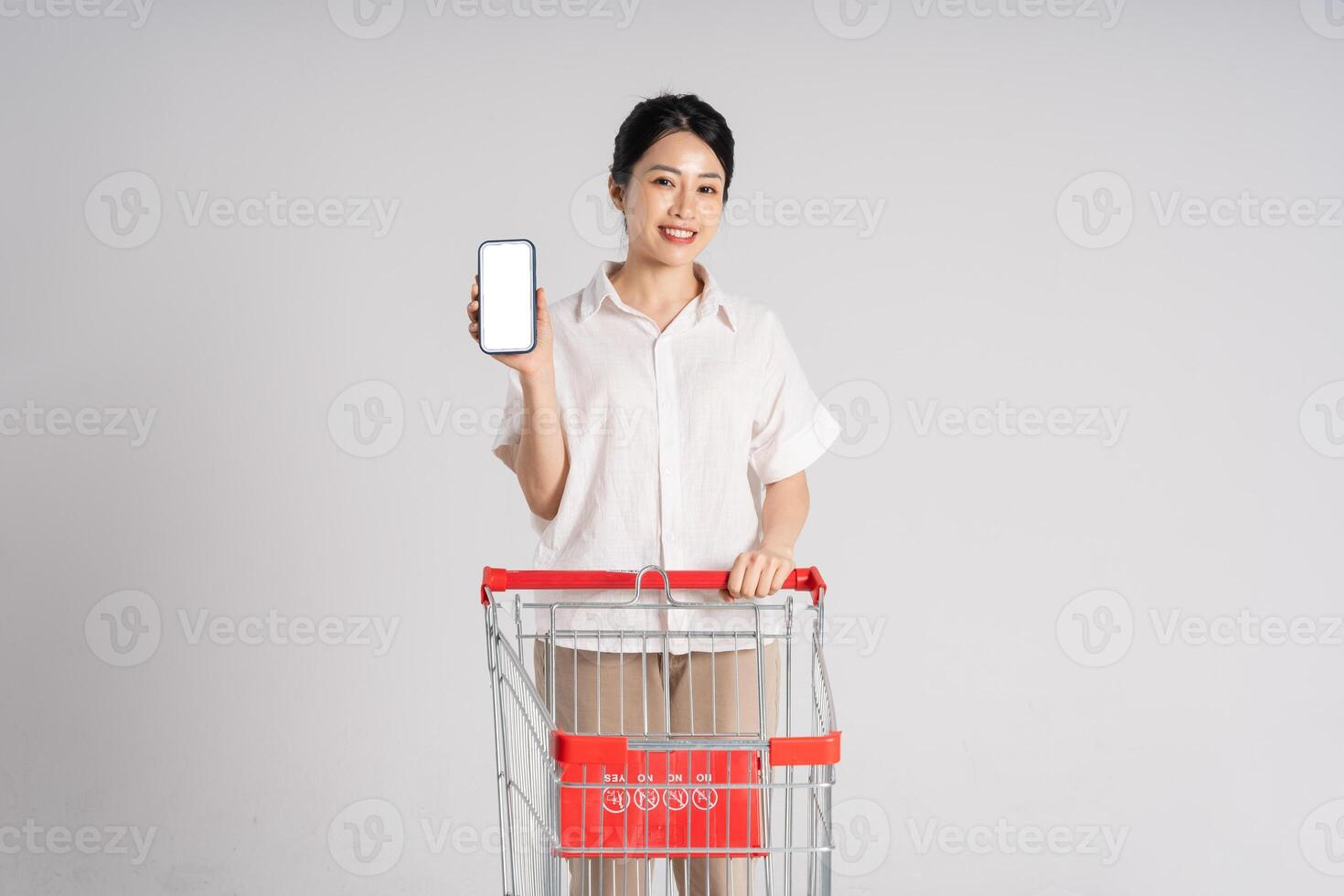 Smiling woman happily pushing a supermarket cart, isolated on white background photo