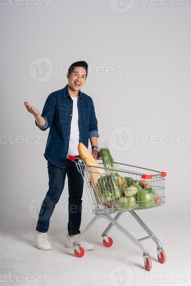 Happy smiling man pushing supermarket cart isolated on white background photo