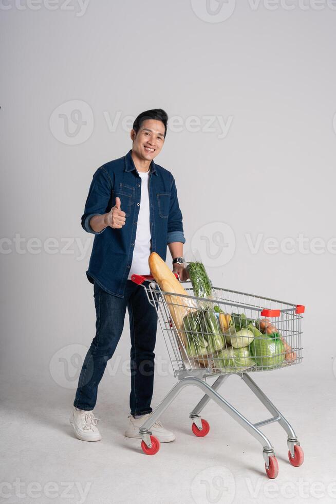 Happy smiling man pushing supermarket cart isolated on white background photo