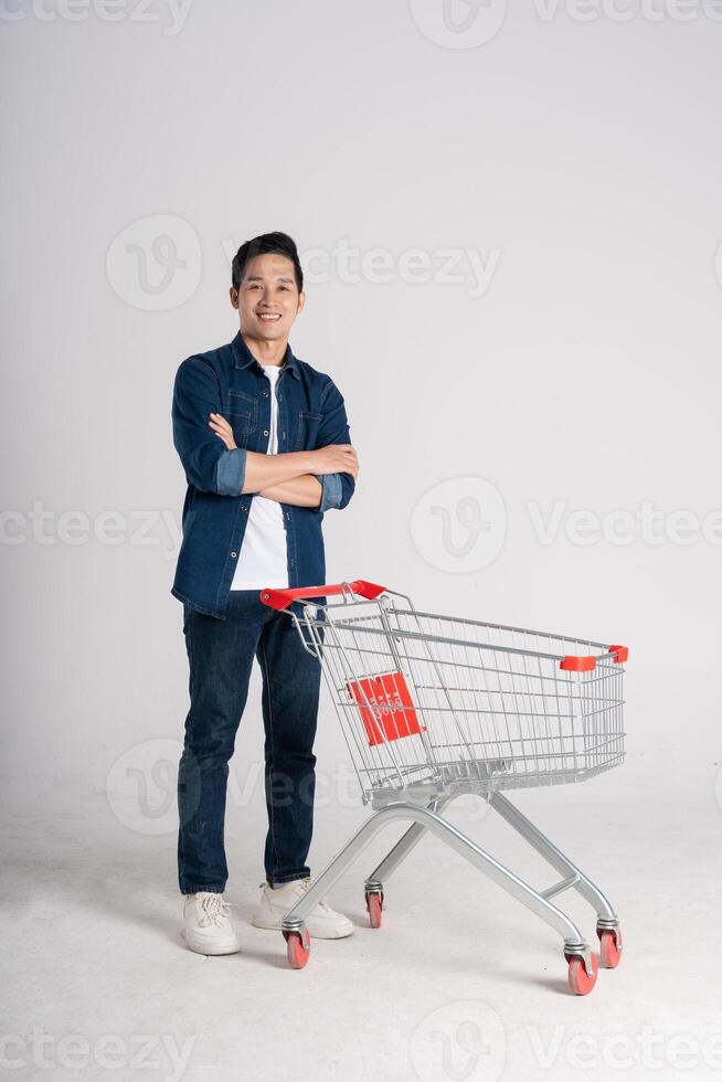 Happy smiling man pushing supermarket cart isolated on white background photo