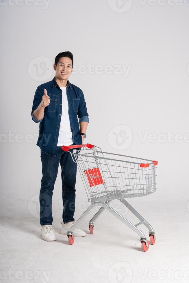 Happy smiling man pushing supermarket cart isolated on white background photo
