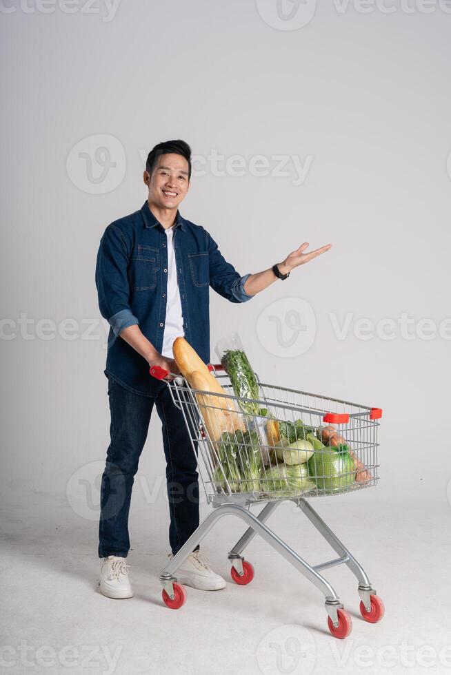 Happy smiling man pushing supermarket cart isolated on white background photo