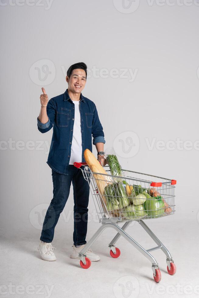 Happy smiling man pushing supermarket cart isolated on white background photo