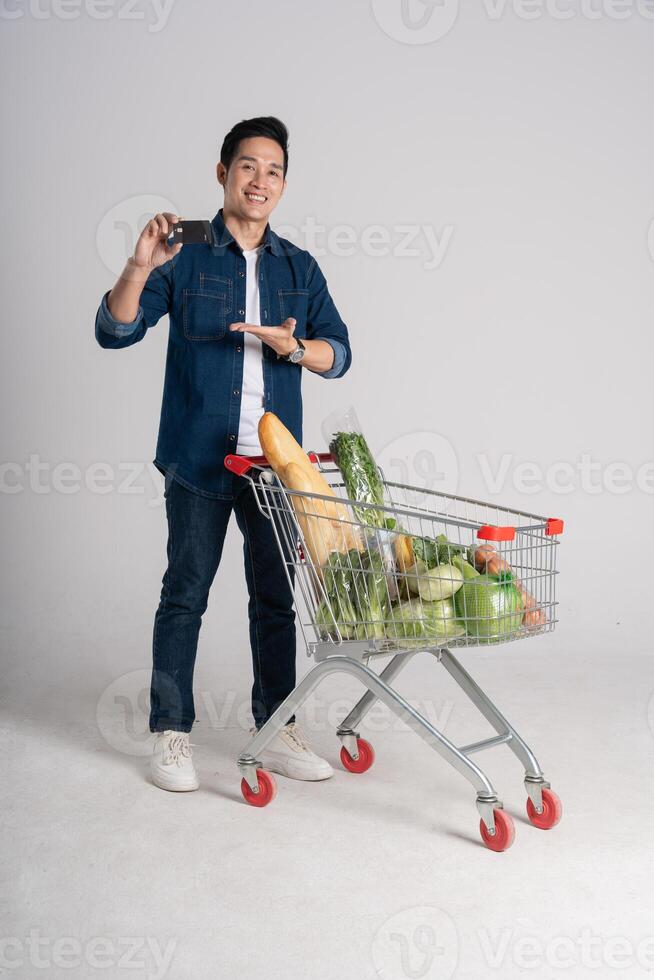 Happy smiling man pushing supermarket cart isolated on white background photo