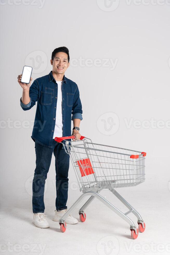 Happy smiling man pushing supermarket cart isolated on white background photo