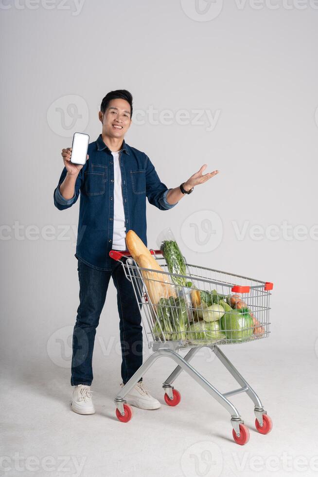 Happy smiling man pushing supermarket cart isolated on white background photo