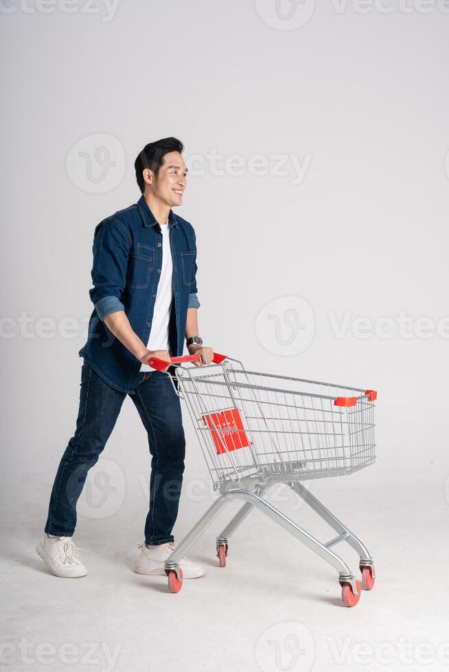 Happy smiling man pushing supermarket cart isolated on white background photo
