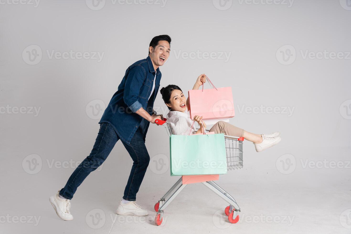 Happy smiling couple pushing supermarket cart isolated on white background photo