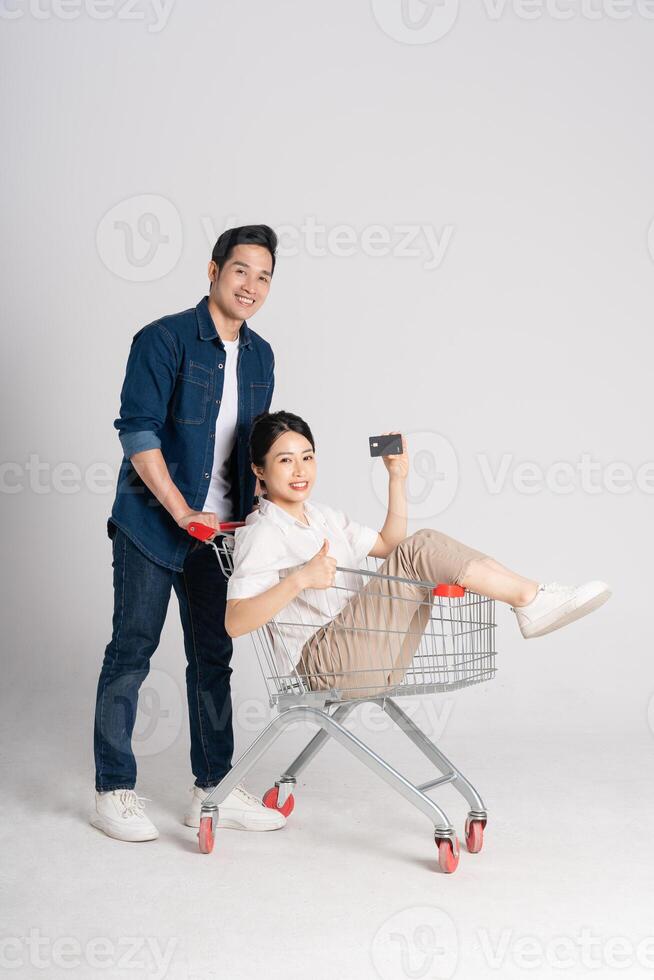 Happy smiling couple pushing supermarket cart isolated on white background photo