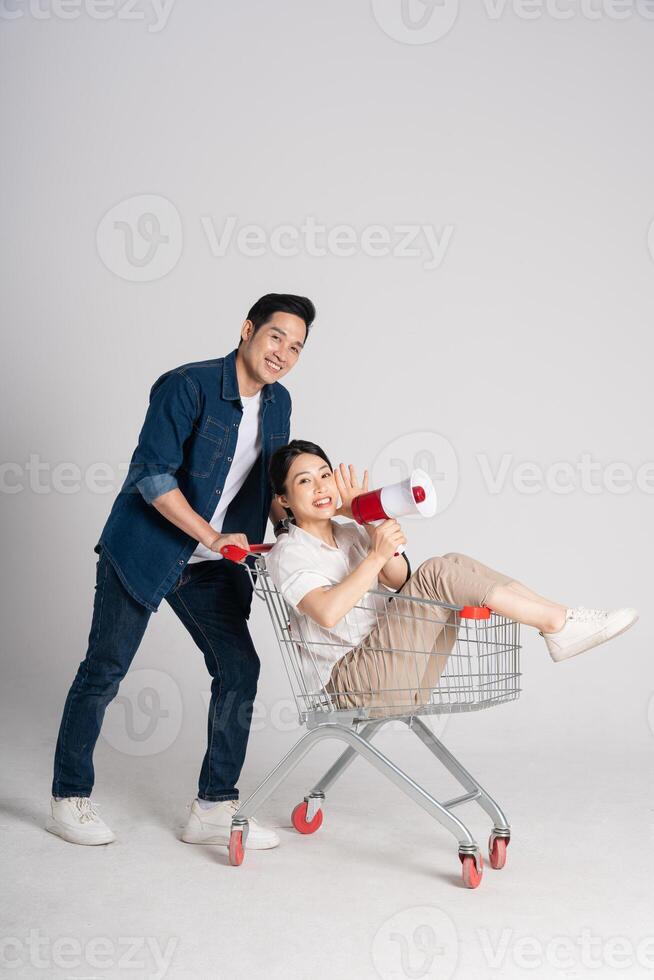 Happy smiling couple pushing supermarket cart isolated on white background photo